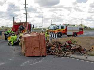 A truck's trailer has rolled on the roundabout connecting Eastern Drive with the westbound lanes of the Warrego Highway, spreading debris across the road. Picture: Dominic Elsome