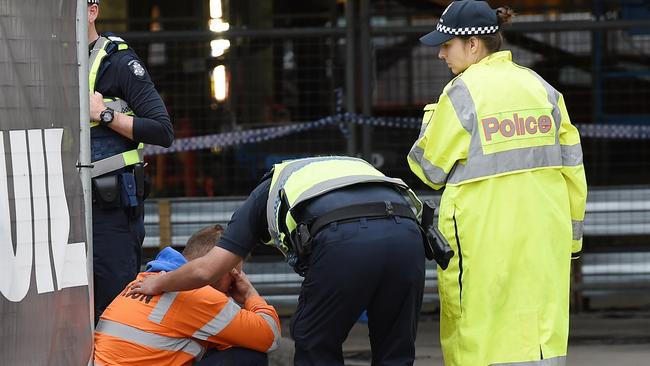 A police officer comforts a construction worker at a site in South Wharf where a worker was killed. Picture: Jake Nowakowski