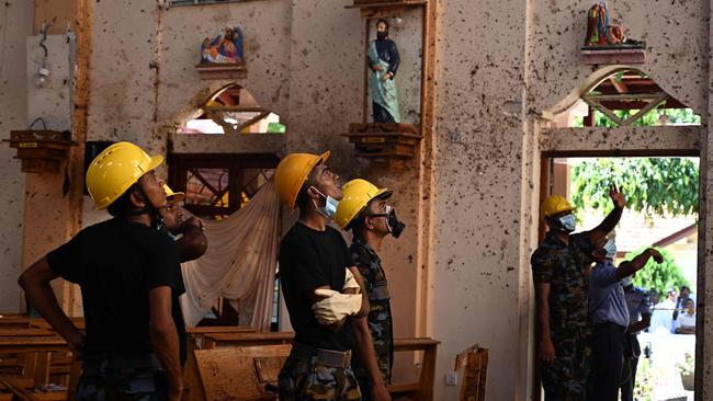 Security staff inspect the interior of St Sebastian's the day after the church was hit in series of bomb blasts. Picture: AFP