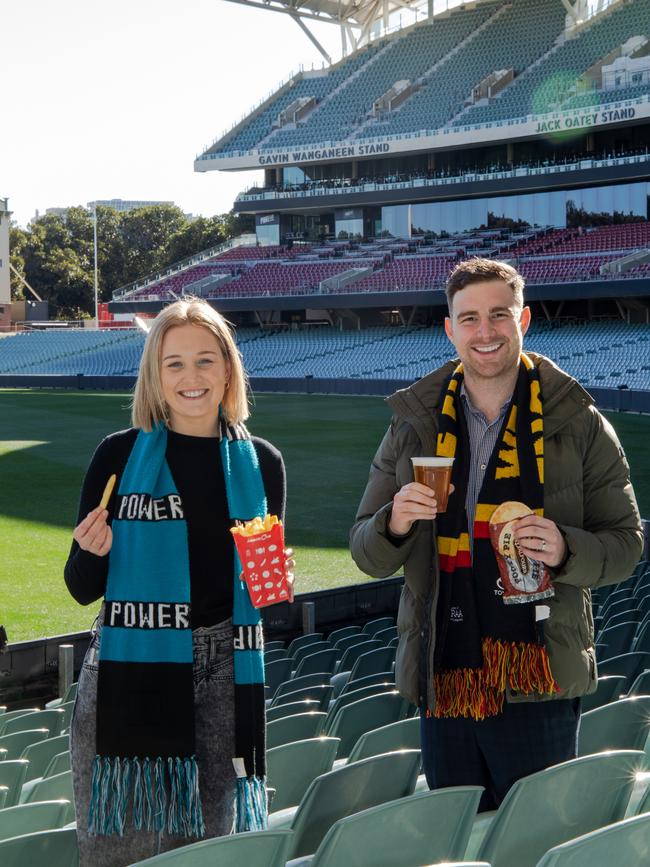 Alice McKeough and Lachlan McLeod celebrating the SMA reducing the price of popular food and beverage items at Adelaide Oval ahead of the AFL returning. Picture: Supplied