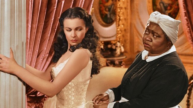 Publicity still from the 1939 film Gone With the Wind showing Scarlett (Vivien Leigh) being laced into a corset by Mammy (Hattie McDaniel).