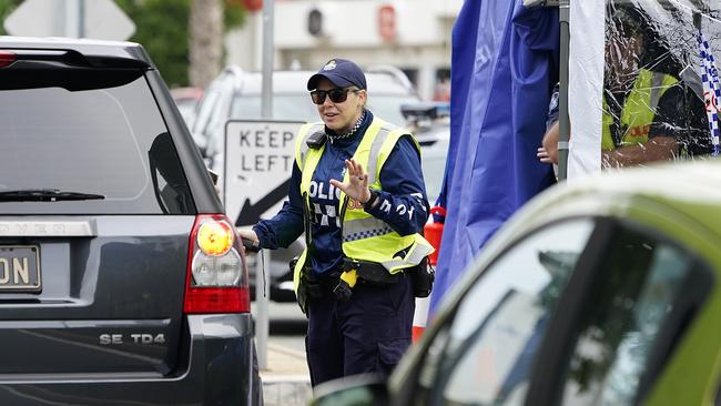 A police officer stopping cars at the border in Coolangatta. Picture: AAP.