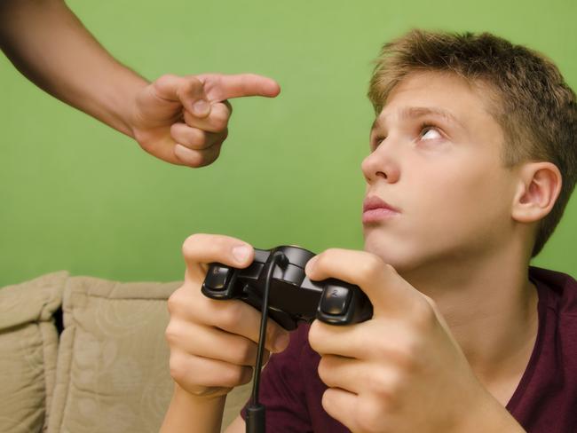 Parent schooling his kid not to play video games. Kid with sad face looking up. Picture: Istock