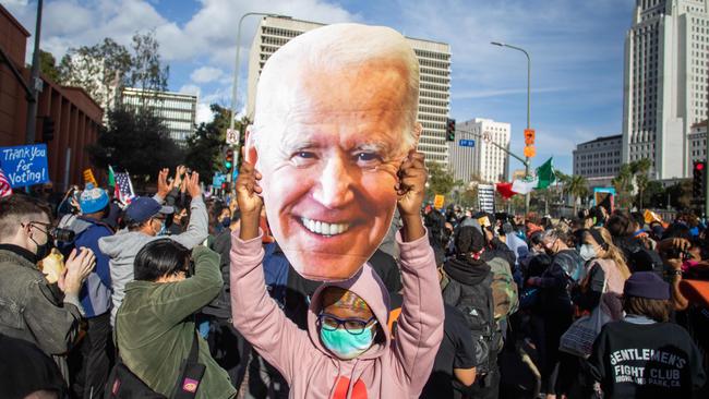 A woman holds a Joe Biden mask as people march in Los Angeles celebrating the Democrat’s victory.