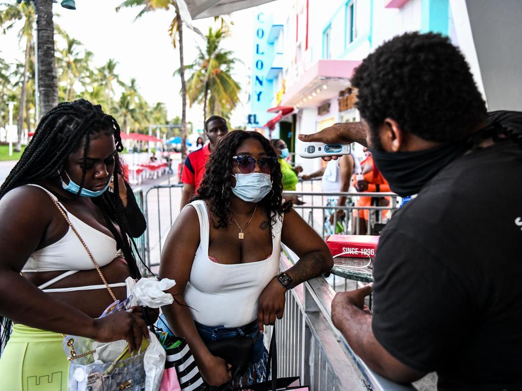 A security guard checks the temperature of a woman at the entrance of a restaurant in Miami Beach. Picture: AFP