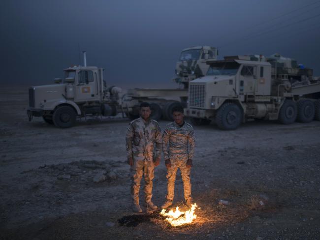 Iraqi army soldiers warm themselves next to a fire near the Qayara air base, south of Mosul. Picture: AP Photo/Felipe Dana