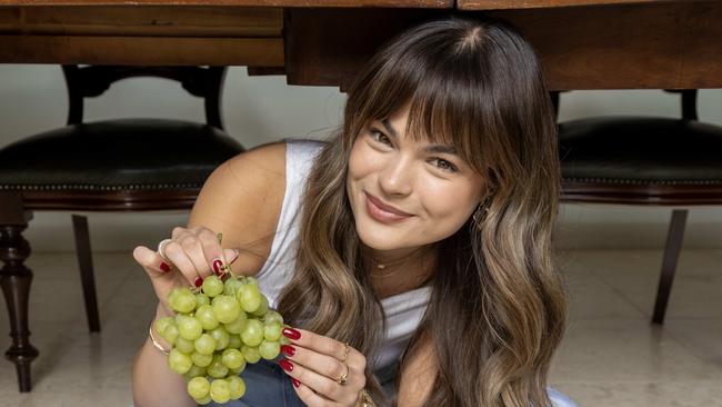 December 30, 2024: Emily Ross, 24, keen to manifest love and luck in 2025 by following the Tik Tok challenge of eating grapes under a table on New Years Eve.  Picture: Kelly Barnes