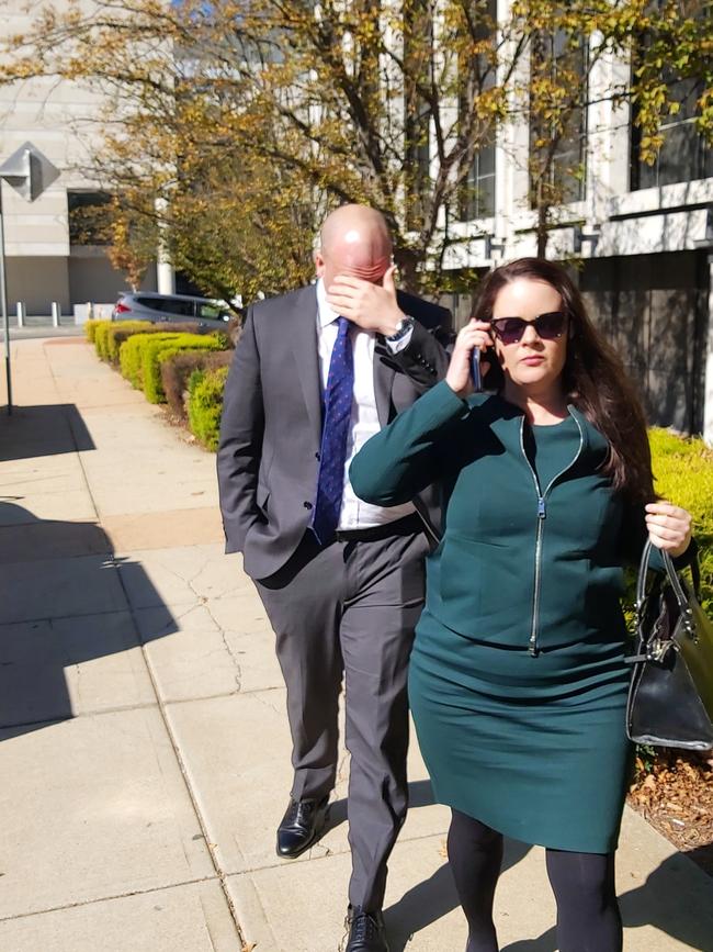 Australian diplomat Neal Kretschmann (left) covers his face as he leaves the ACT Magistrates Court, while his partner attempts to contact police. Picture: Craig Dunlop