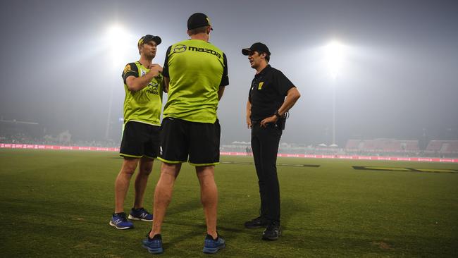 Officials discuss the smoke haze during the BBL game at Manuka Oval on Saturday. Picture: AAP