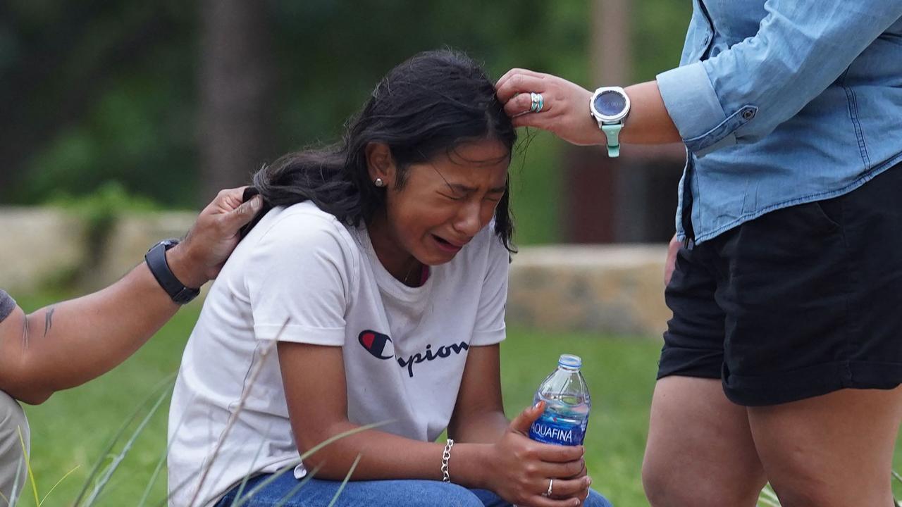 A girl cries, comforted by two adults, outside the Willie de Leon Civic Centre where grief counseling will be offered in Uvalde, Texas, on May 24, 2022. Picture: by Allison Dinner / AFP