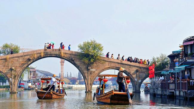 Sightseeing boats take tourists under the Fangsheng Bridge in the water town of Zhujiajiao, Shanghai.