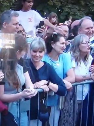 The woman smirks at the person next to her after Meghan has passed.