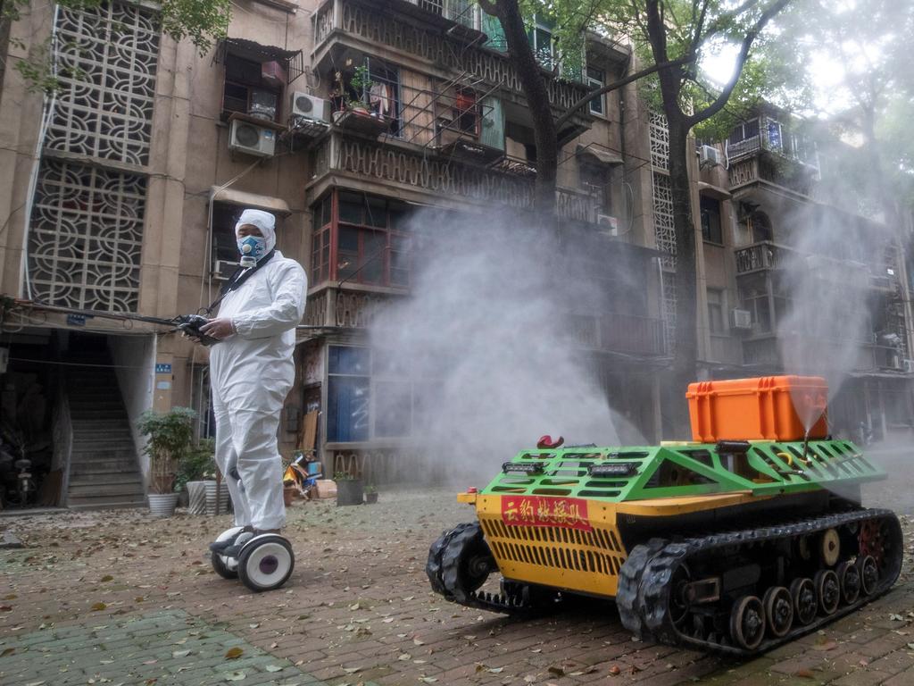 A volunteer operates a remote controlled disinfection robot to disinfect a residential area in Wuhan. Picture: STR / AFP