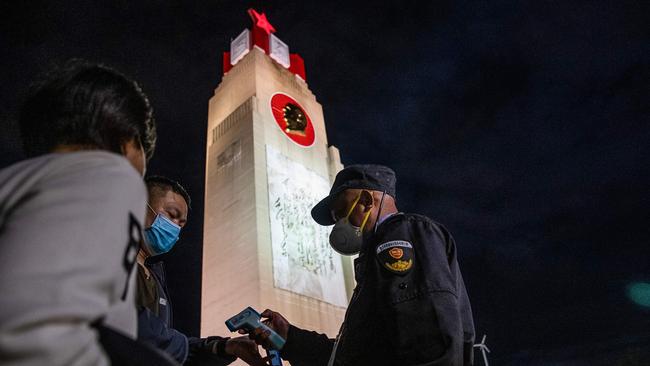 A security guard checking the body temperature of a visitor at the Beach Park in Wuhan on March 27. Picture: AFP