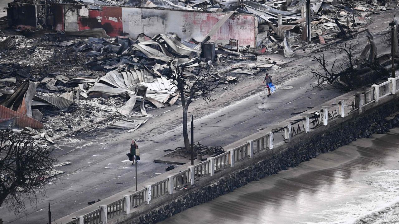 A person walking down Front Street past destroyed buildings burned to the ground in Lahaina in the aftermath of wildfires in western Maui, Hawaii. (Photo by Patrick T. Fallon / AFP)