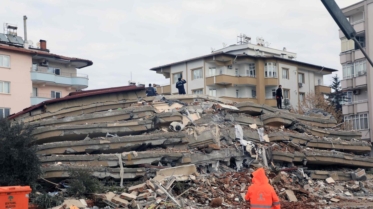 Rescuers stand on top of the rubble of collapsed building in Gaziantep. (Photo by Zein Al RIFAI / AFP)