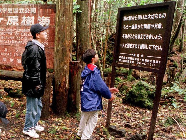 FILE - in this Thursday, Oct. 22, 1998, file photo a group of schoolchildren read signs posted in the dense woods of the Aokigahara Forest at the base of Mount Fuji, Japan. American blogger Logan Paul is apologizing after getting slammed for a video he shared on YouTube that appeared to show a dead body in the Aokigahara Forest in Japan, which is famous as a suicide spot. The sign at right reads: "Your life is a precious gift from your parents. Once again, try to remember your parents, brothers and sisters and think about your children." (AP Photo/Atsushi Tsukada, File)