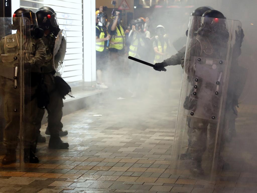 Riot police form up as journalists work nearby among tear gas in Hong Kong. Picture: AP