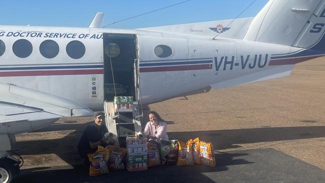 On March 22, Royal Flying Doctor Service pilot Shaun Adamson (left) delivered donated dog food to Burketown so locals including Paula McKinlay (right) holding Flood the puppy, could feed the dogs they rescued after their owners were forced to evacuate when the floods devastated the Gulf. Picture: Supplied