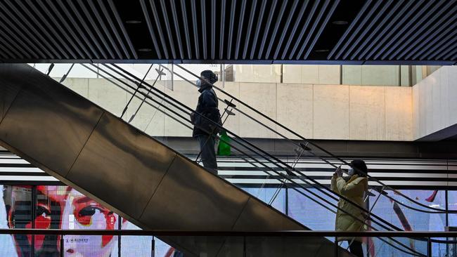 People use an escalator at a shopping mall in Beijing. Picture: AFP