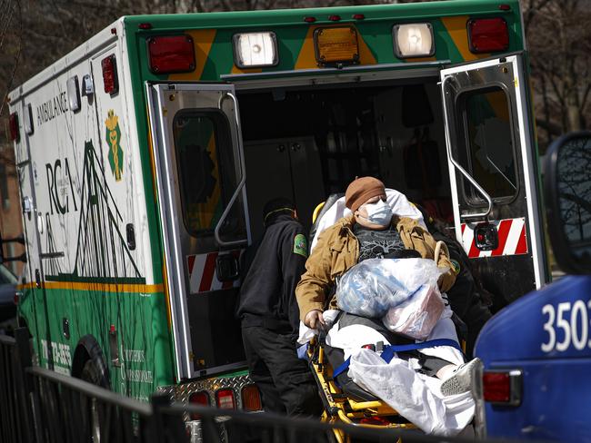 A patient wears a protective face mask as she is loaded into an ambulance at The Brooklyn Hospital Centre emergency room. Picture: AP