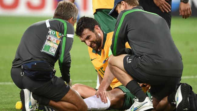 Mile Jedinak receives treatment after rolling his ankle in the game against Kuwait.