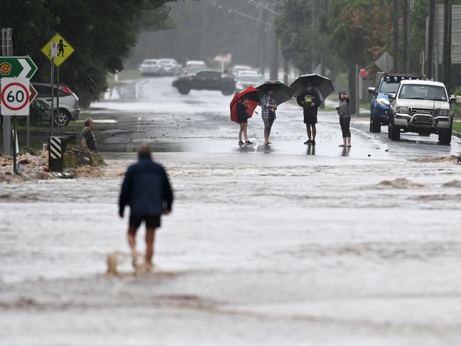 Locals inspect a road cut off by floodwater on May 13, 2022 in Laidley. (Photo by Dan Peled/Getty Images)