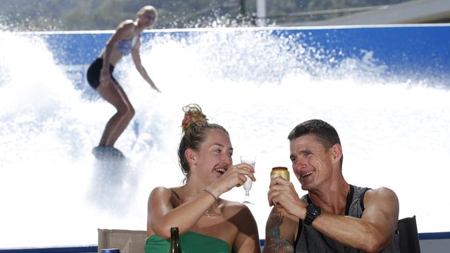 Brenna Hyde and Matt Armstrong enjoy a cold drink at the licensed area at the Flowrider at The Tobruk Pool while Flowrider lifeguard Shannon Quaife has a ride. Picture: Cairns Post