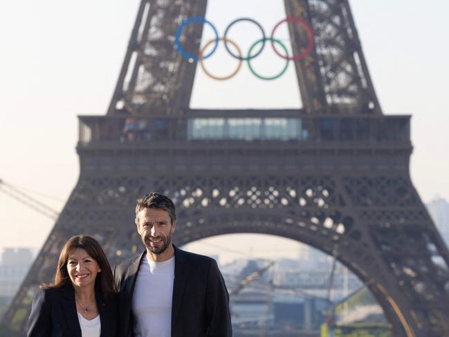 Paris mayor Anne Hidalgo and French President of the Paris 2024 Olympics and Paralympics Organising Committee (Cojo) Tony Estanguet pose in front of the Eiffel Tower after the installation of the Olympic rings on the tower for the upcoming Paris 2024 Olympic Games, in Paris on June 7, 2024. (Photo by JOEL SAGET / AFP)