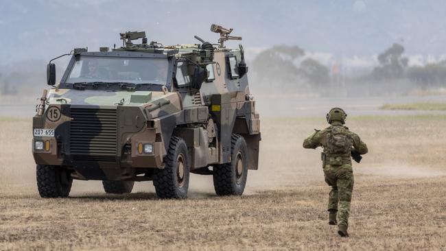 An airfield defence guard from No. 1 Security Forces Squadron moves towards a Bushmaster Protected Mobility Vehicle.