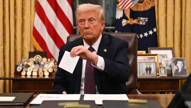 US President Donald Trump holds up outgoing President Joe Biden's letter as he signs executive orders in the Oval Office. Picture: AFP