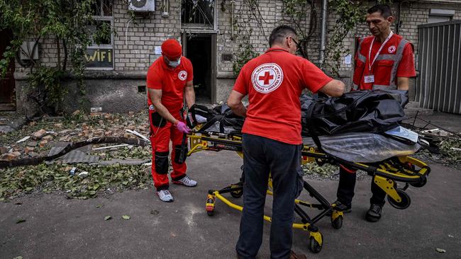 Red Cross workers carry the body of woman killed in a residential building that was shelled in the city of Mykolaiv on Saturday. Picture: AFP