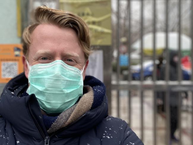 The Australian's journalist Will Glasgow in Beijing with signs warning about coronavirus in the background in 2020.