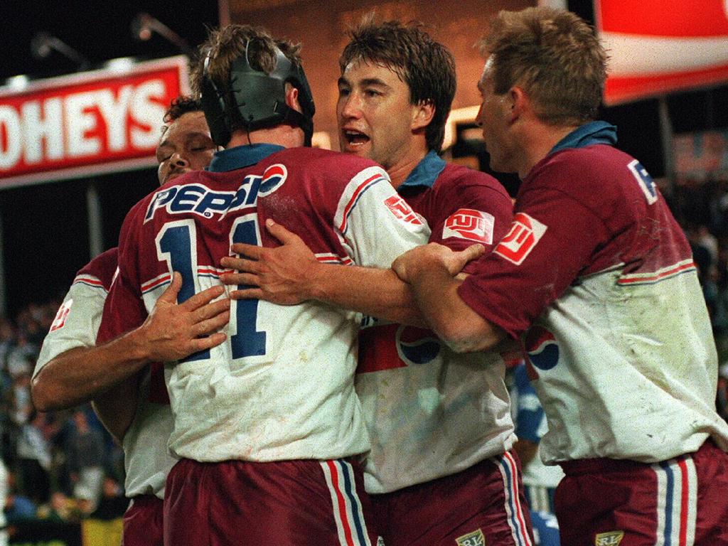 Terry Hill is embraced by Steve Menzies and Manly teammates.