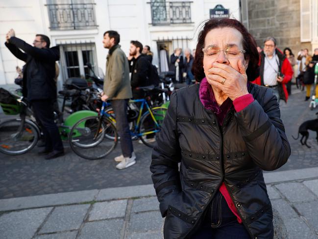 A woman reacts as she watches flames engulf the roof of the Notre-Dame de Paris Cathedral in the French capital Paris on April 15, 2019.(Photo by GEOFFROY VAN DER HASSELT / AFP)
