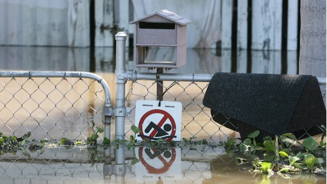 A 'no swimming' sign on the fence of one flooded home seems to state the obvious.