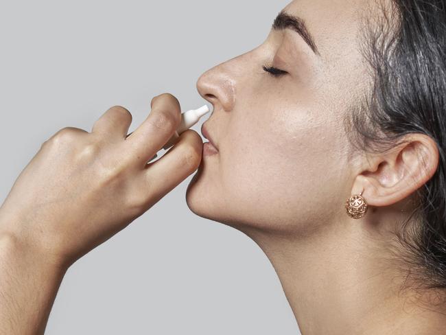 Woman using nasal spray. A woman using a nasal spray to decongest her nose. Sick woman using nasal spray. Woman using nose spray