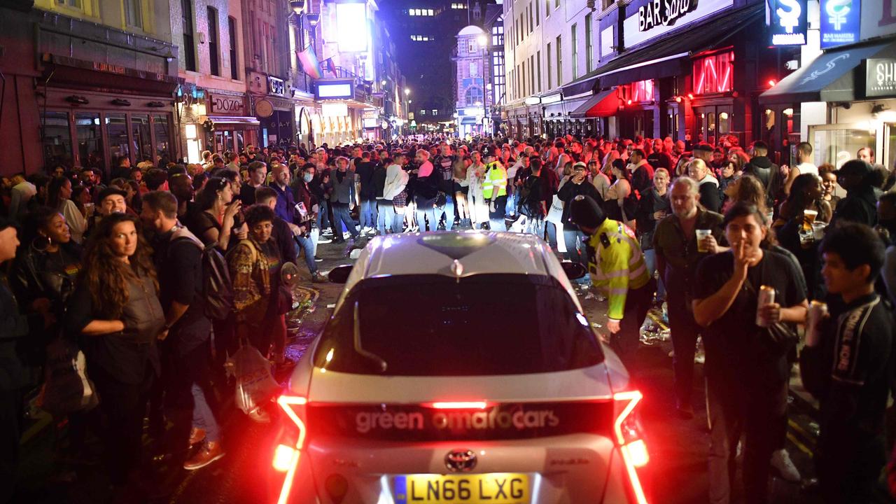 A car tries to drive along a street filled with revellers drinking in the Soho area of London. Picture: AFP