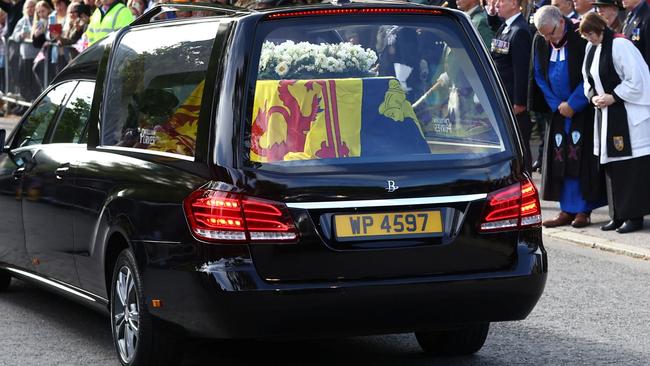 People line the street as the hearse carrying the coffin of Britain's Queen Elizabeth passes through the village of Ballater, near Balmoral, Scotland, on Sunday night (AEST). Picture: Reuters