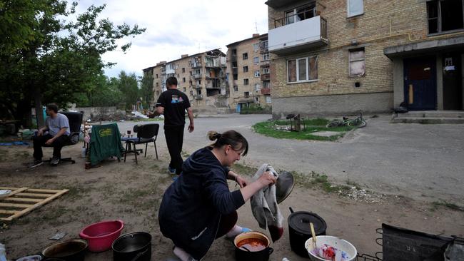 A Ukrainian woman cooks outside her damaged building because of the lack of electricity and gas, in the small town of Moshchun, not far from Kyiv. Picture: AFP