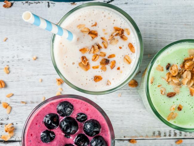 Refreshing milkshakes or smoothies: White (banana), green (apple and kiwi) and berries; with fresh fruits. On a white wooden table, copy space