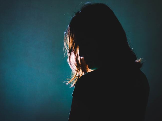 silhouette of depress woman standing in the dark with light shine behind