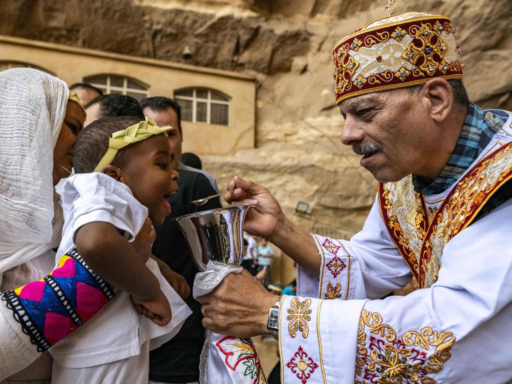 An Ethiopian Orthodox worshipper holds up a child receiving communion during the Palm Sunday service in Cairo, marking the start of Holy Week. Picture: Khaled Desouki/AFP