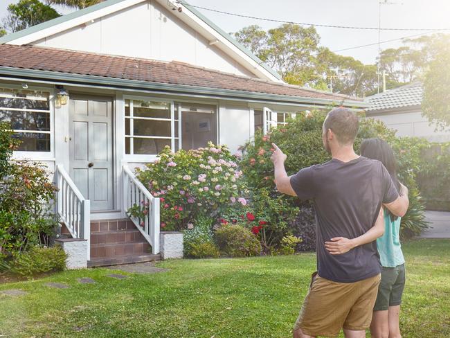 Happy mixed-race couple standing in front of house.