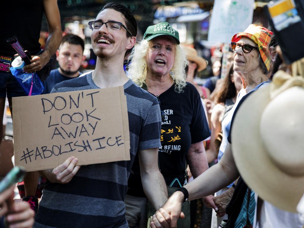 People holds hands as they chant at a rally before the start of a march in opposition to the Trump administration's plans to continue with raids to catch immigrants in the country illegally. Picture: AP Photo/Julius Constantine Motal.