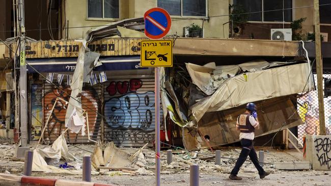 An Israeli rescuer walks in front of a damaged shop in Tel Aviv, after it was hit by a rocket fired by Palestinian militants from the Gaza Strip on October 7, 2023. Picture: AFP