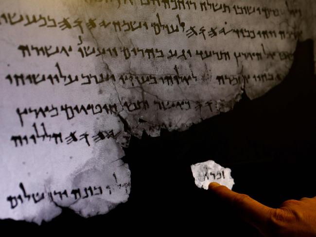 An Israel Antiquities Authority staff member points at an infra-red scan of a fragment of a Dead Sea Scroll next to a larger one, with a previously unseen hidden text. Picture: Gali Tibbon