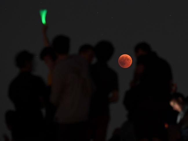 People watch the total lunar eclipse in the Olympic park in Munich, southern Germany. Picture: AFP