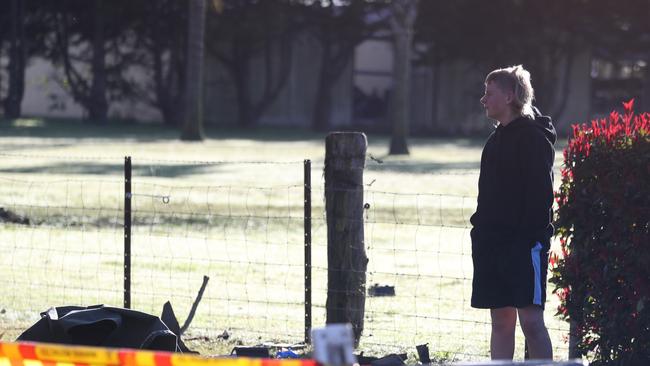 People arrive at the scene with flowers. Picture: John Grainger