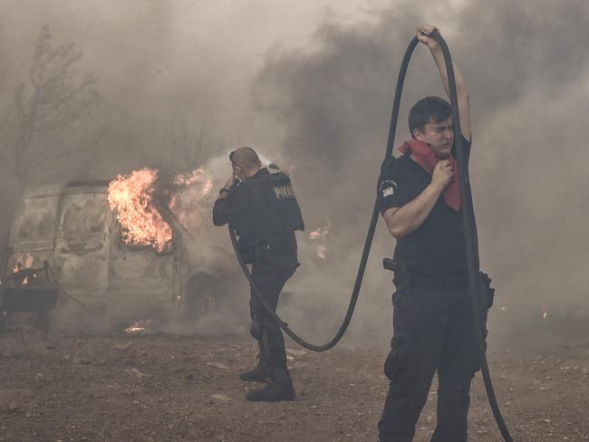 Police officers battle the raging fire in Lagonisi area, some 35 kilometeres from Athens, on July 17, 2023. Greek police on July 17, 2023 arrested a man suspected of starting an ongoing wildfire near Athens fuelled by a heatwave and strong winds, firefighters said. "Police carried out the arrest of a foreigner who allegedly caused the fire" in Kouvaras, around 50 kilometres (30 miles) southeast of Athens, said fire service spokesman Yannis Artopios. (Photo by Spyros BAKALIS / AFP)